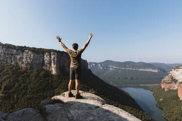 Man with arms raised standing on mountain against clear sky at Vilanova de Sau,  Catalonia, Spain - MOSF00121