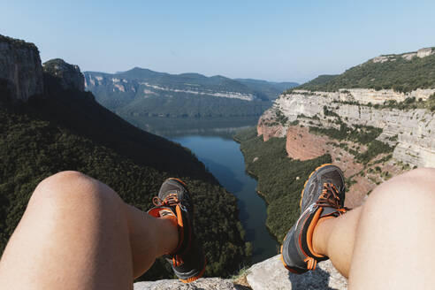 Legs of man sitting on mountain against clear sky at Vilanova de Sau,  Catalonia, Spain - MOSF00122