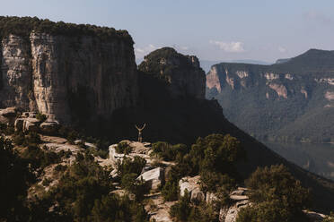 Mid distance of man with arms raised standing on mountain at Vilanova de Sau,  Catalonia, Spain - MOSF00123