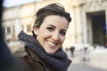 Junge fröhliche Frau in Winterkleidung nimmt ein Selfie mit Smartphone im Freien in Mailand Italien - ADSF08245