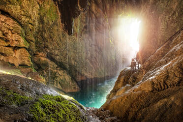 Scenic tropical cave with underground river and pathway with railing in sunlight - ADSF08413