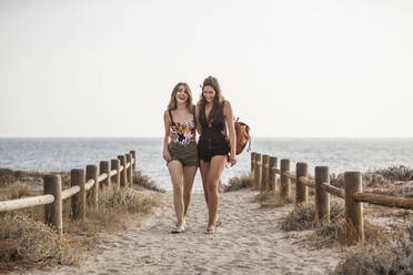 Frauen mit Rucksack zu Fuß in der Nähe von hölzernen Zaun umarmt einander beim Chatten und Lächeln auf Natur Seeküste Hintergrund - ADSF08463