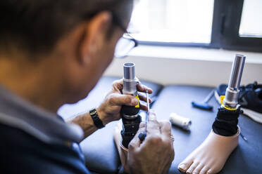 Prosthetic engineer reviewing the prosthesis of a patient and improving the material in his workshop - ADSF08490