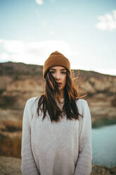 Youthful charming female tourist looking at camera while enjoying weekend journey to lake in autumn - ADSF08532