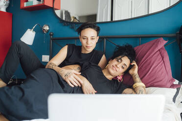 Lesbisches Paar schaut auf Laptop im Schlafzimmer - MEUF01762