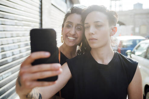 Lächelnde Frau und Partner nehmen Selfie in der Stadt - MEUF01776