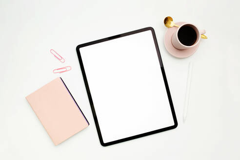 Draufsicht auf moderne Tablet mit leeren Bildschirm auf weißem Hintergrund mit Notebook und Tasse Espresso platziert - ADSF08564