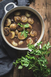 Von oben Kochtopf mit Boeuf Bourgingnon mit Pilzen und grünen Kräutern auf Holztisch - ADSF08651