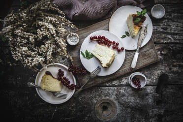 Von oben servierte Käsekuchenstücke auf Teller mit Beeren auf dunklem Holztisch - ADSF08679