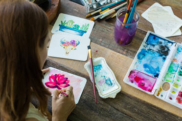 Lateinamerikanische Künstlerin malt mit Aquarellfarben in ihrem Atelier - ADSF08693