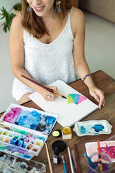 Latin artist painting with watercolor in her studio - ADSF08698
