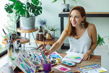 Latin artist painting with watercolor in her studio - ADSF08699