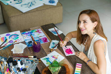 Lateinamerikanische Künstlerin malt mit Aquarellfarben in ihrem Atelier - ADSF08700