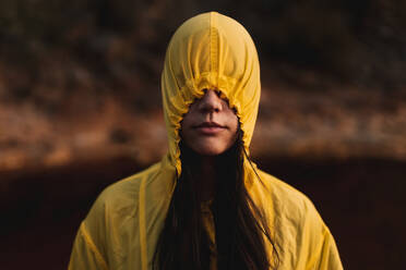 Young lady in yellow raincoat strolling in nature - ADSF08755