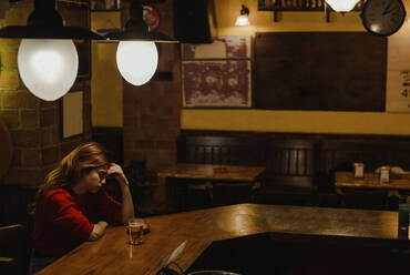 Sad woman with beer glass on bar counter sitting in restaurant - LJF01722