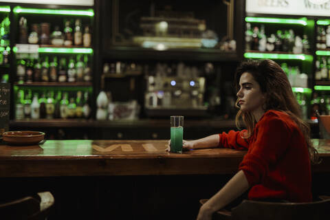 Nachdenkliche Frau mit Getränk auf dem Tresen im Restaurant sitzend, lizenzfreies Stockfoto