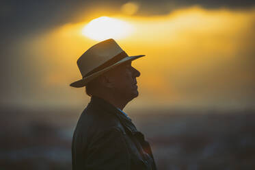 Älterer Mann mit Hut gegen den Himmel bei Sonnenuntergang - OCMF01599