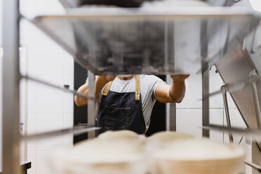 Männlicher Bäcker in Schürze in einer Bäckerei - MRRF00170