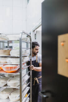 Baker working in commercial kitchen at bakery - MRRF00172