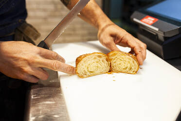 Bäcker schneidet Brot über dem Küchentisch einer Bäckerei - MRRF00202