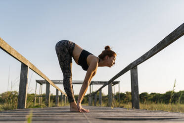 Woman exercising on pier at countryside - EGAF00617