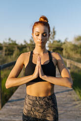 Woman meditating with hands clasped outdoors - EGAF00618