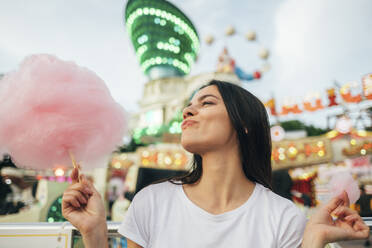 Nahaufnahme einer jungen Frau, die in einem Vergnügungspark Zuckerwatte isst - OYF00191