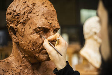 Hand of sculptor finishing a clay head eye - CAVF87866