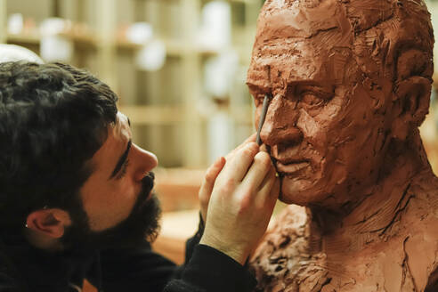 Focused sculptor finishing a clay head - CAVF87867