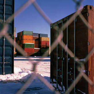 Im Winter hinter dem Zaun gestapelte Schiffscontainer - CAVF87905