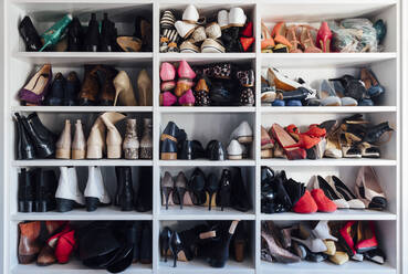 Modern white closet and square shelves with female colorful expensive high heels shoes and sneakers - ADSF08791
