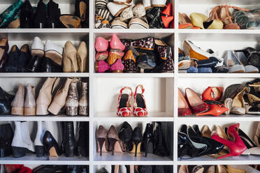 Modern white closet and square shelves with female colorful expensive high heels shoes and sneakers - ADSF08793