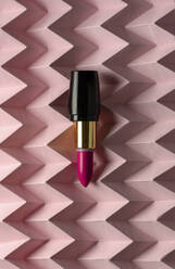 Lippenstift auf erhöhtem rosa Chevron: Produkt- und Make-up-Konzept - ADSF08813