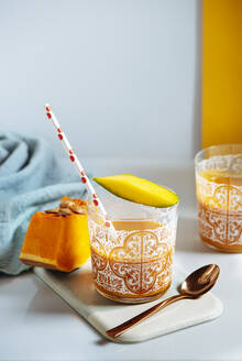 Mango und Pump-Smoothie in einem Glas, umgeben von Obst und Gemüse, gesundes Lebenskonzept - ADSF08818