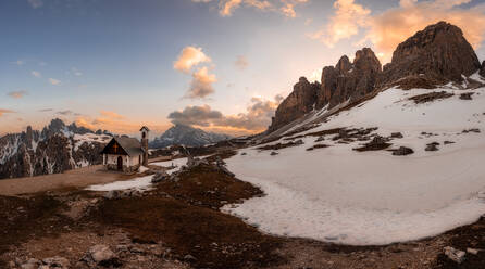 Berglandschaft mit ländlichem Haus in einem verschneiten Tal, umgeben von gefährlichen Felsen unter offenem, bewölktem Himmel in den Dolomiten Italien - ADSF08835