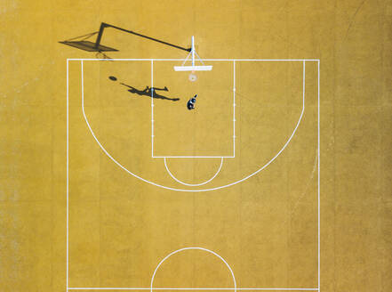 Young man playing basketball on outdoor court. Top view, bird eye view of yellow basketball court - ADSF08854