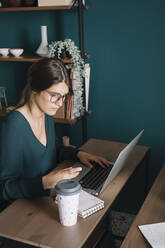 Young woman using laptop on desk at home - ALBF01319