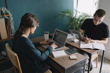 Young man and woman working on desks at home - ALBF01322