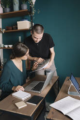 Junger Mann und Frau besprechen Papier im Heimbüro - ALBF01323