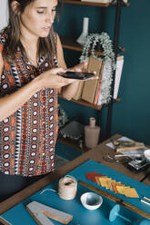 Junge kreative Frau, die ein Smartphone-Foto von einer Dekoration auf dem Tisch macht - ALBF01327