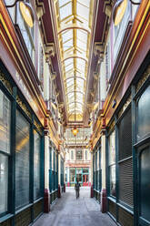 Eine Frau geht durch den Leadenhall Market, einen von Horace Jones entworfenen viktorianischen Markt, City of London, London, England, Vereinigtes Königreich, Europa - RHPLF17248