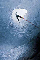 Mann beim Abseilen in eine Gletscherhöhle auf dem Sólheimajökull-Gletscher in Island - CAVF87938