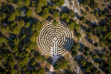Luftaufnahme eines von Bäumen umgebenen labyrinthförmigen Gartens in Rogoznica, Kroatien - AAEF09237
