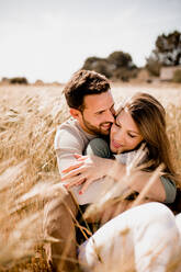 Sinnlich liebender Mann und Frau umarmen sich auf Roggenfeld im Sommer auf unscharfem Hintergrund - ADSF08874