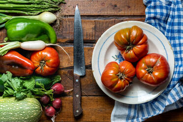 Fresh organic vegetables on a dark wooden table with tomatoes in a bowl and a knife - ADSF08881