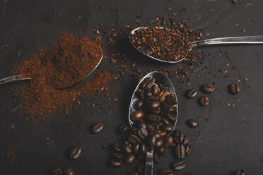 Arten von Kaffeesatz Instant und Pulver und Kaffeebohnen in Löffeln auf schwarzem Tisch - ADSF08900
