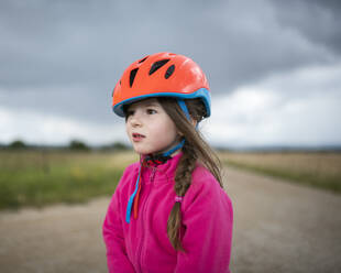 Mädchen mit orangefarbenem Fahrradhelm schaut zur Seite - BRF01480