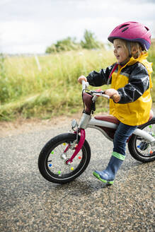 Toddler girl with pink cycling helmet on balance bicycle - BRF01483