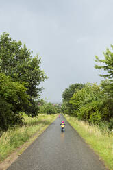 Mädchen mit Fahrrad und Gleichgewichtsfahrrad auf dem Fahrradweg bei Regenwetter - BRF01484