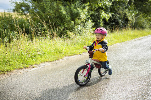 Kleinkind-Mädchen mit rosa Fahrradhelm auf Balance-Fahrrad, lizenzfreies Stockfoto